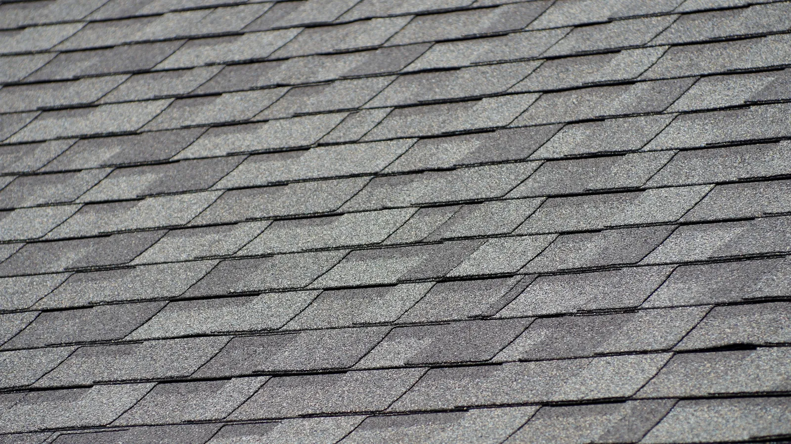 Gray architectural asphalt shingles in overlapping rows seen from overhead