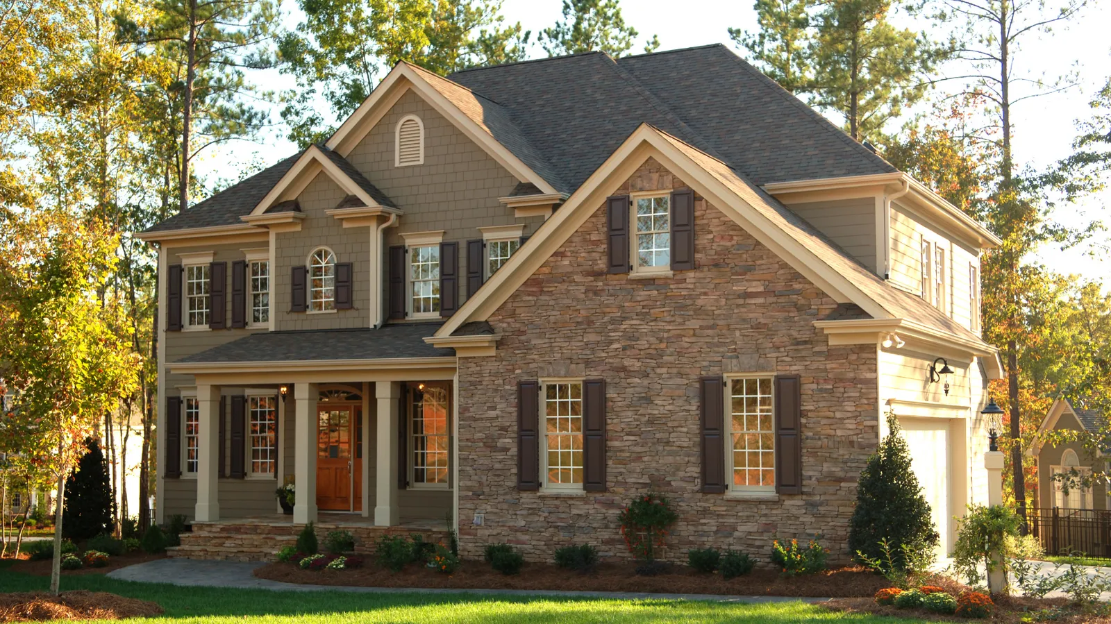 Stone and siding two-story home beneath a brown shingle roof