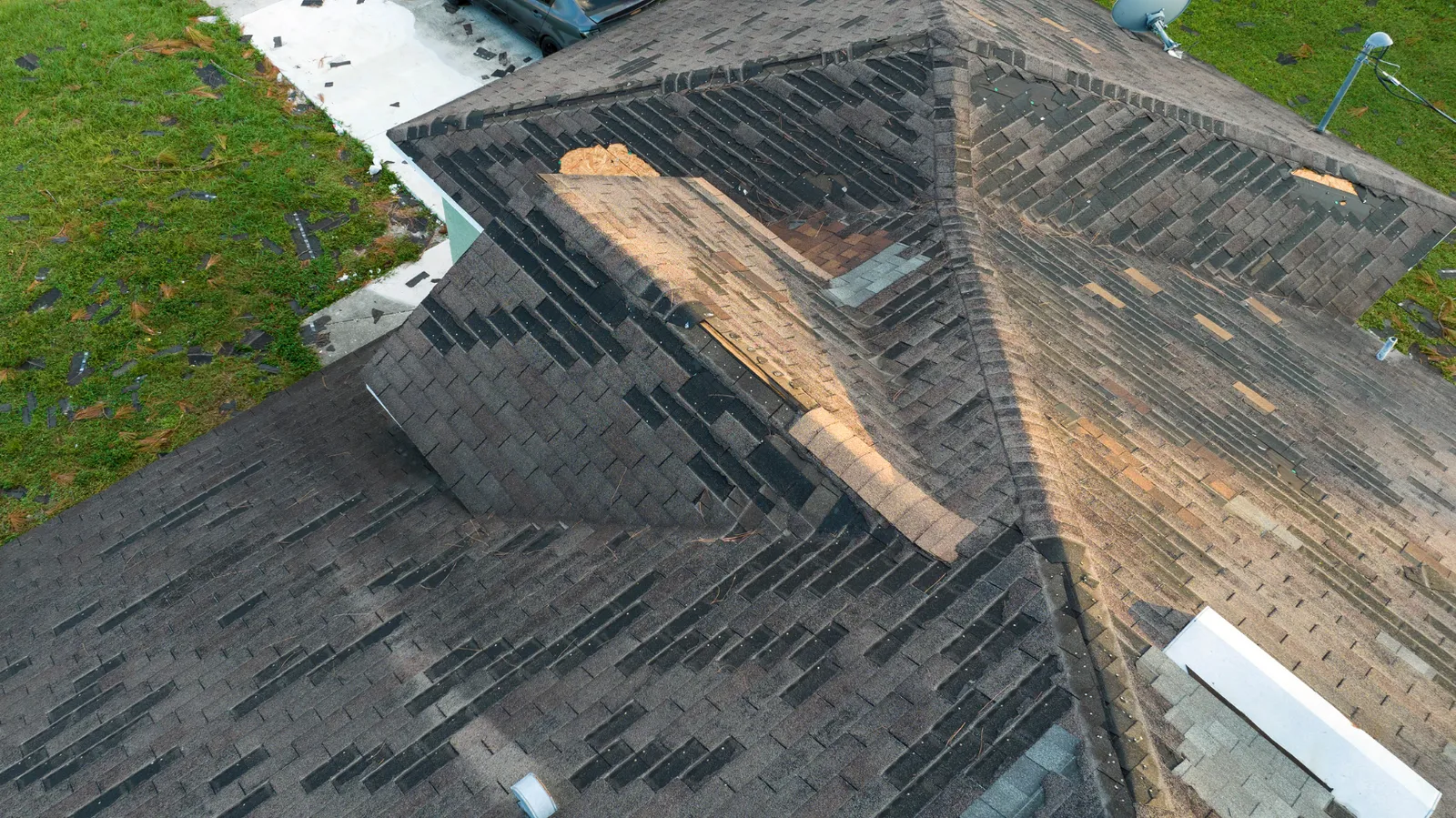 Shingles stripped to bare wood across roof valleys and ridges